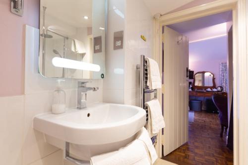 a white bathroom with a sink and a mirror at Frogs Hall B&B in Eye