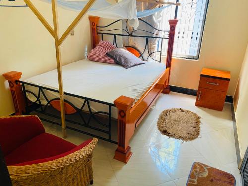 um quarto com uma cama de dossel e uma cadeira em MKOLANI RELINI em Mwanza