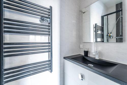 een badkamer met een zwarte wastafel en een spiegel bij luxueux appartement haussmannien in Saint-Mandé