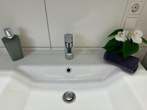 a white sink with a faucet and flowers on it at Ferienwohnungen GoJa in Bad Königshofen im Grabfeld