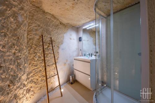 a bathroom with a glass shower and a sink at La Troglo - Maison typique de notre région in Vouvray