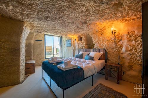 ein Schlafzimmer mit einem Bett in einer Steinmauer in der Unterkunft La Troglo - Maison typique de notre région in Vouvray