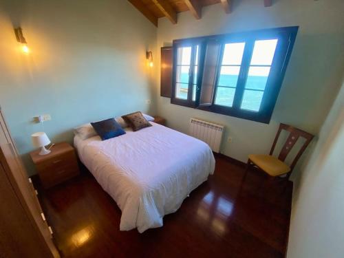 a bedroom with a white bed and a window at El balcón del Escanu in Lastres