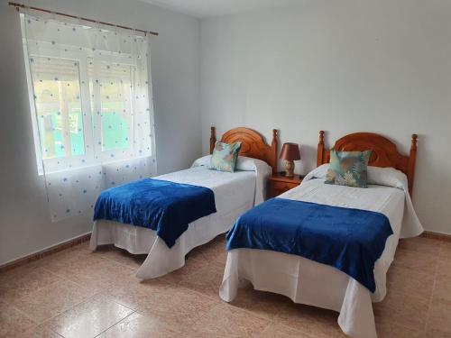 a bedroom with two beds and a window at Piso da Charca in Fisterra