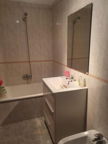 a bathroom with a sink and a mirror and a tub at Piso da Charca in Fisterra