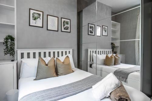 Duas camas num quarto com paredes brancas e espelhos em Livestay-Charming London Retreat Stylish 1BR near Kings Cross&Farrington em Londres