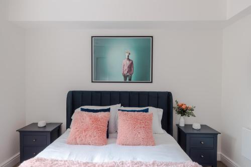 Un dormitorio con una cama con almohadas rosas y una foto en Frankie Says - London lodgings don't get more fabulous than the Fitz n' Glamour, a dazzling 1 BR apartment in central Fitzrovia, en Londres