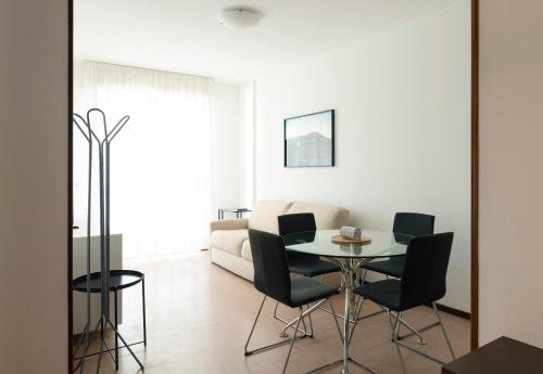 ein weißes Wohnzimmer mit einem Tisch und Stühlen in der Unterkunft 54 Bilocale con ampio Terrazzo a 50 metri dal mare in Lignano Sabbiadoro