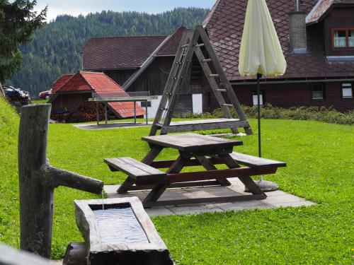 a picnic table with a ladder and an umbrella at Biohof Stockreiter vulgo Grillschmied in Murau