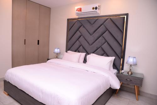 1 dormitorio con 1 cama blanca grande y cabecero grande en Tom's Luxury, en Peshawar