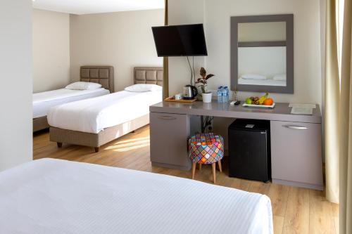 a hotel room with two beds and a desk with a mirror at Mene City Hotel in Antalya