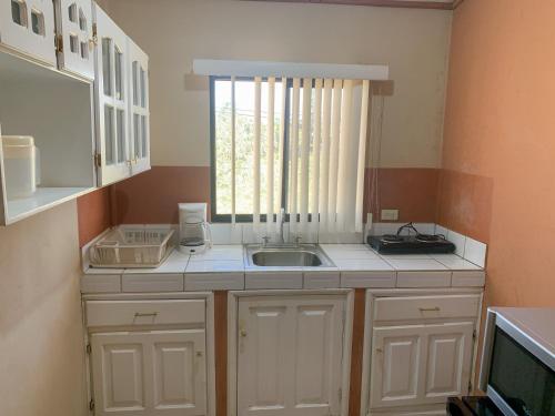 uma pequena cozinha com um lavatório e uma janela em Apart-Hotel Plaza Familiar em La Esperanza