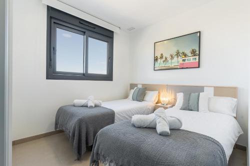 two twin beds in a room with a window at Arenales Bahia Penthouse in Arenales del Sol