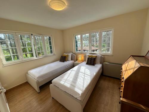 ein Zimmer mit 2 Betten und einem Sofa darin in der Unterkunft Golf, Pool and Beach Aroeira Villa in Aroeira