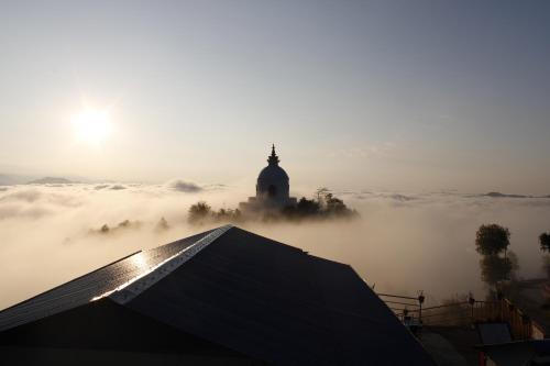 a foggy view of a building in the distance with a building in the background at Mountain View cafe in Pokhara