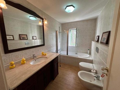 ein Badezimmer mit einem Waschbecken, einer Badewanne und einem Spiegel in der Unterkunft Golf, Pool and Beach Aroeira Villa in Aroeira