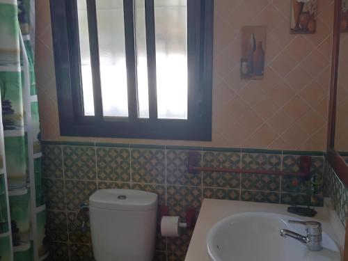 łazienka z toaletą, umywalką i oknem w obiekcie Chalet con piscina privada en Conil Solo Familias w mieście Conil de la Frontera
