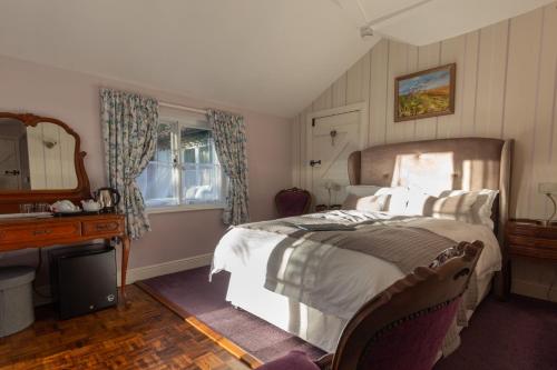 een slaapkamer met een bed, een bureau en een spiegel bij Frogs Hall B&B in Eye