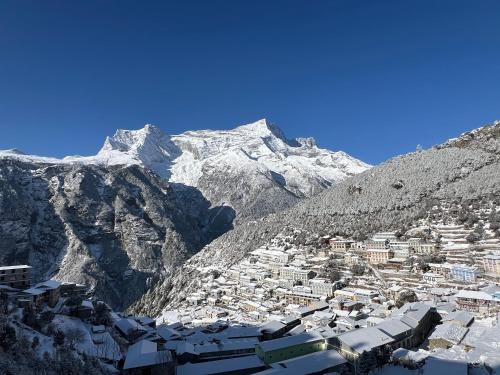 un pueblo en las montañas con montañas cubiertas de nieve en Namche Terrace, en Namche