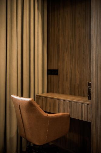 a brown chair sitting in a room with curtains at Central Park Apartments - The Luxury Collection in Kaunas