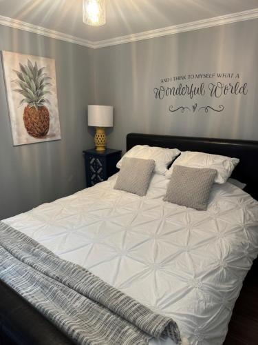 Un dormitorio con una cama blanca con una piña en la pared en Lazy Days Vacation Rental, en Picton