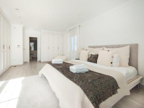 een witte slaapkamer met een groot bed met witte kussens bij Villa del Prado Private Pool Large Garden in Marbella