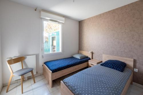 een slaapkamer met 2 bedden, een stoel en een raam bij Le Jardin des Chimères in Castanet-Tolosan