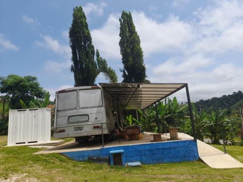 uma caravana estacionada ao lado de uma cerca e árvores em Chalé Bus Ponto Z em São Bento do Sapucaí