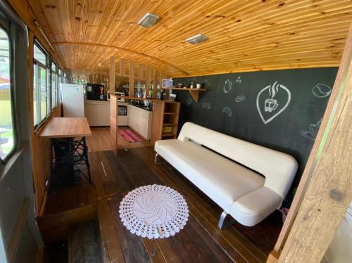 uma sala de estar com um sofá e uma cozinha em Chalé Bus Ponto Z em São Bento do Sapucaí