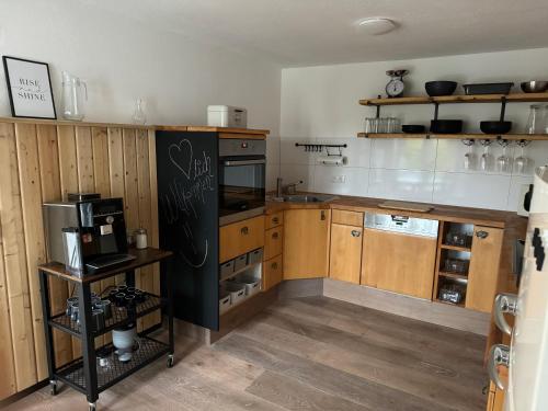 a kitchen with wooden cabinets and a black refrigerator at Willkommen im Alpen Relax in Obergünzburg