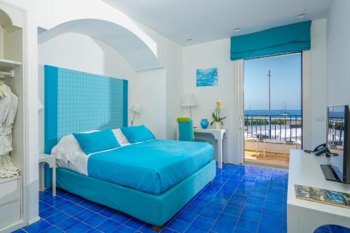 a bedroom with a blue bed and a balcony at Le Ancore Hotel in Vico Equense