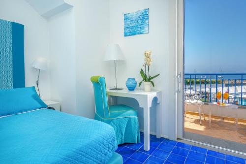a bedroom with a bed and a desk and a balcony at Le Ancore Hotel in Vico Equense