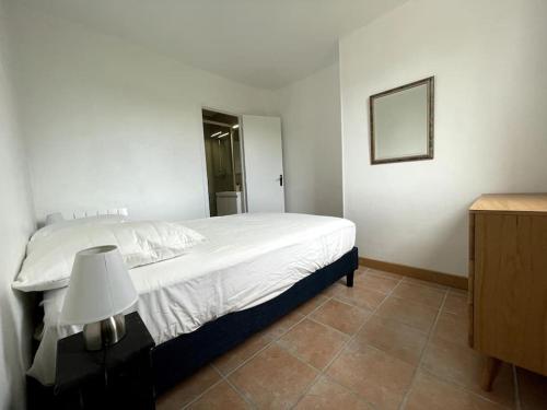 Un dormitorio con una cama blanca y una lámpara. en Charmant logement avec parking privé., en Veules-les-Roses