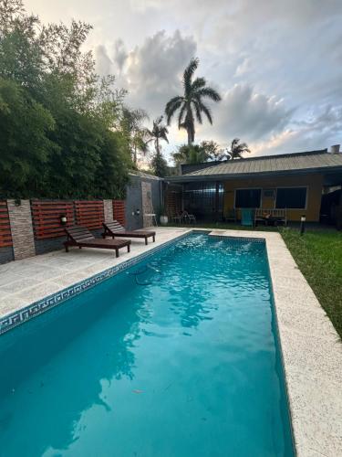 einen Pool mit Bänken neben einem Haus in der Unterkunft Casa en Paso de la Patria in San Cosme