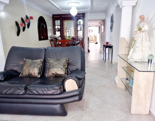 a black leather couch in a living room with a statue at Hermosa casa en Bucaramanga in Bucaramanga