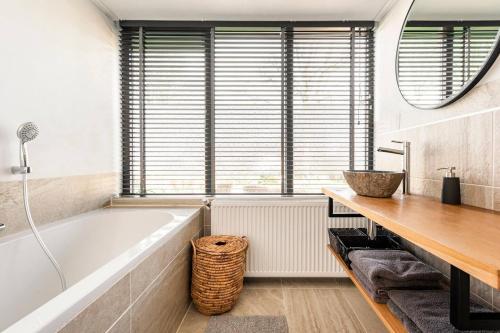 ein Badezimmer mit einer Badewanne und einem Waschbecken in der Unterkunft Enjoy Heuvelland in Simpelveld