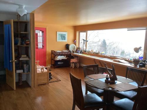 ein Wohnzimmer mit einem Tisch und einem großen Fenster in der Unterkunft Le Remous in La Malbaie