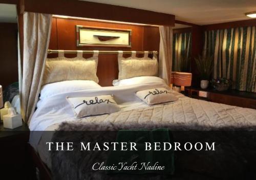 a bedroom with a large bed with white sheets and pillows at Classic Yacht Nadine in Poole Harbour, Dorset, with a Hot Tub Jacuzzi in Poole