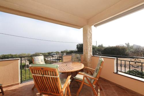 a balcony with a wooden table and chairs at Apartman Sipina 1 in Kukljica