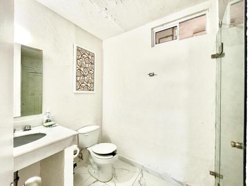 a white bathroom with a toilet and a sink at Departamento con vista al mar in Mazatlán