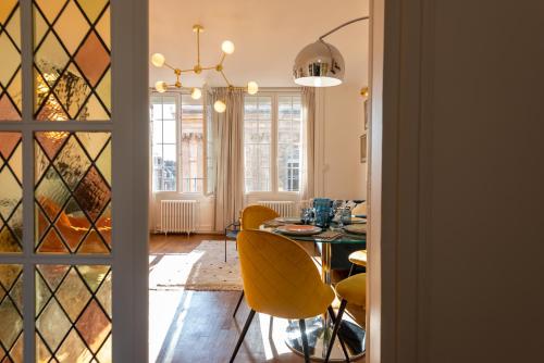 une salle à manger avec une table et des chaises jaunes dans l'établissement Luxueux 3ch - Hôtel de ville, à Amiens