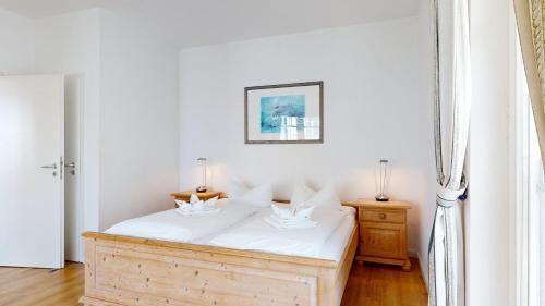 a bedroom with a wooden bed with white sheets at Haus Saxonia in Binz
