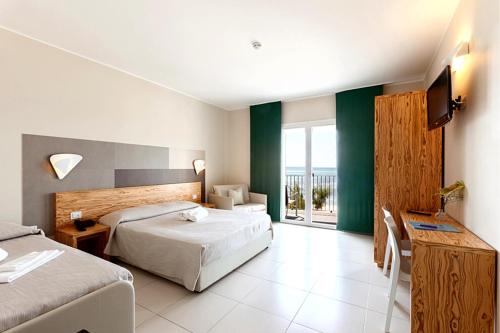 a hotel room with two beds and a balcony at Hotel la Spiaggia in Torre Lapillo