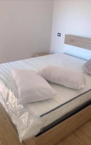 Una cama con sábanas blancas y almohadas. en House Beach, en Campomorto