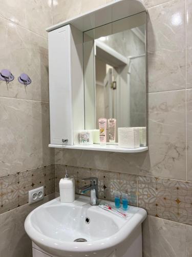a bathroom with a white sink and a mirror at Байзакова 133 in Pavlodar