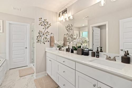 a white bathroom with a sink and a mirror at Copper Creek Retreat - Hot Tub - Fenced In Yard in Fayetteville