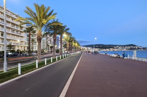 une rue avec des palmiers sur le côté d'une plage dans l'établissement 1 Min to the Beach Apartment - Kitchen - Tramway - Air Conditioner - Wifi - Promenade Des Anglais, à Nice