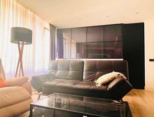 a living room with a leather couch and a glass table at SMALL LUX BEACHCITY CLOSE to the RIVER,METRO AND PARKING in Bilbao