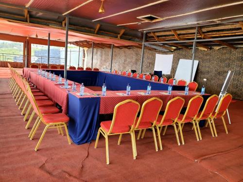 une grande table avec des chaises rouges et une table bleue dans l'établissement Galore Luxury Resort, à Maseno