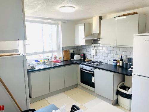 eine Küche mit weißen Schränken, einem Waschbecken und einem Fenster in der Unterkunft Double Room Near Tower Bridge 403 in London